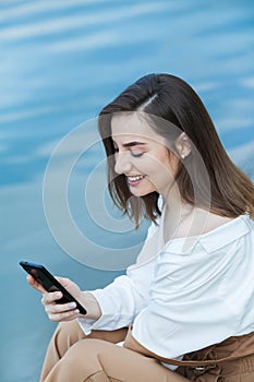 Girl outdoors texting on her mobile phone. Girl with phone. Portrait of a happy woman text sms message on her phone.