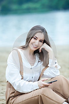 Girl outdoors texting on her mobile phone. Girl with phone. Portrait of a happy woman text sms message on her phone.