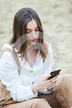 Girl outdoors texting on her mobile phone. Girl with phone. Portrait of a happy woman text sms message on her phone.