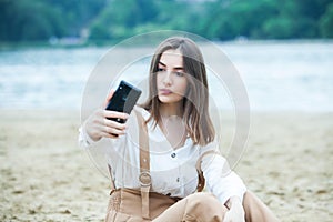 Girl outdoors texting on her mobile phone. Girl with phone. Portrait of a happy woman text sms message on her phone.