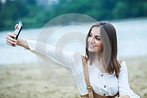 Girl outdoors texting on her mobile phone. Girl with phone. Portrait of a happy woman text sms message on her phone.