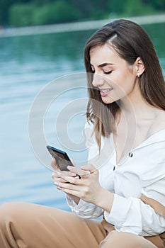 Girl outdoors texting on her mobile phone. Girl with phone. Portrait of a happy woman text sms message on her phone.