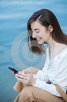 Girl outdoors texting on her mobile phone. Girl with phone. Portrait of a happy woman text sms message on her phone.