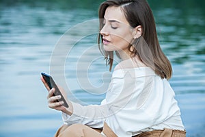 Girl outdoors texting on her mobile phone. Girl with phone. Portrait of a happy woman text sms message on her phone.