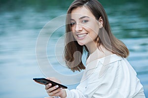 Girl outdoors texting on her mobile phone. Girl with phone. Portrait of a happy woman text sms message on her phone.