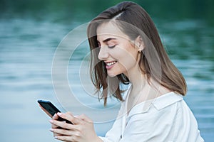 Girl outdoors texting on her mobile phone. Girl with phone. Portrait of a happy woman text sms message on her phone.