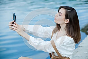 Girl outdoors texting on her mobile phone. Girl with phone. Portrait of a happy woman text sms message on her phone.