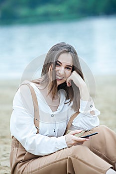 Girl outdoors texting on her mobile phone. Girl with phone. Portrait of a happy woman text sms message on her phone.