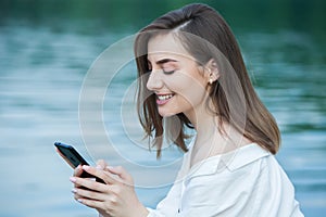 Girl outdoors texting on her mobile phone. Girl with phone. Portrait of a happy woman text sms message on her phone.