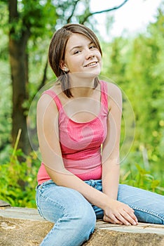 Girl outdoors in woods sitting on log