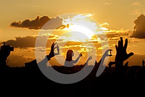 Girl over the crowd against the sunset sky. Having fun and using her smartphone at the summer festival