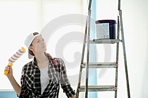 Girl painter, designer and worker paints a roller and brush the wall.