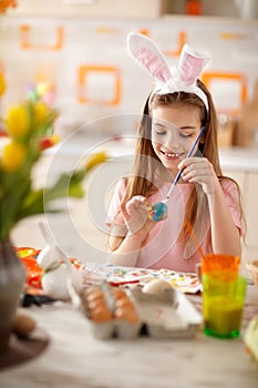 Girl painting egg in blue for Easter festivity photo