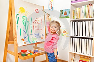 Girl painting with green brush at the easel