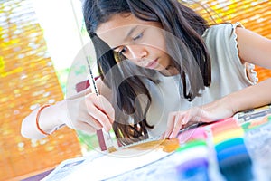 Girl painting a paper plate with poster paint