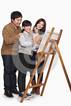 Girl painting with parents, studio shot