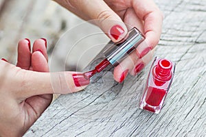 The girl paints nails in a fashionable red color. Trendy manicure colors_
