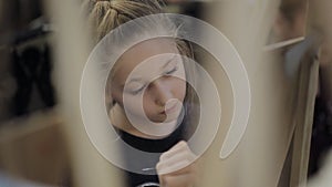 The girl paints a picture in the children`s studio of fine art .. Many easels and canvases on the table.