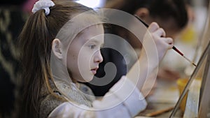 The girl paints a picture in the children`s studio of fine art .. Many easels and canvases on the table.