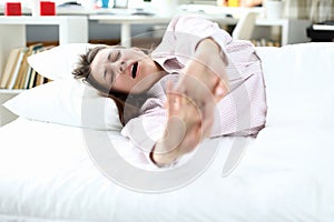 Girl in pajamas lies on bed and stretches, yawning