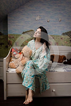 Girl in pajamas sitting on the bed with toys