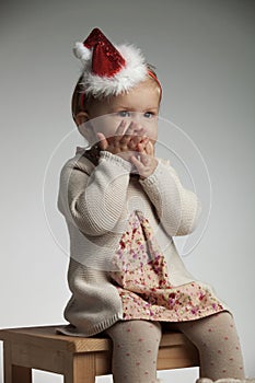 Girl with palms over her mouth is expecting santa claus