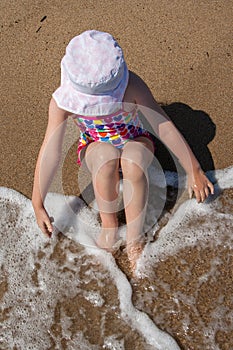 Girl in a Panama hat sit on the beach.