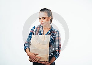 Girl with paper bags. Consumerism symbol. Photo from the side. Brown paper bag. heckered shirt.