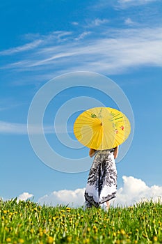 Girl with parasol on meadow looking