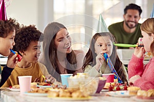 Girl With Parents And Friends At Home Celebrating Birthday With Party And Blowers