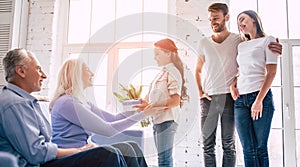 The girl with parents giving a gift with flowers to grandparents.