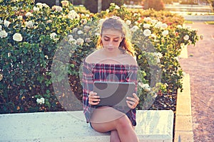 Girl on park bench playing with tablet