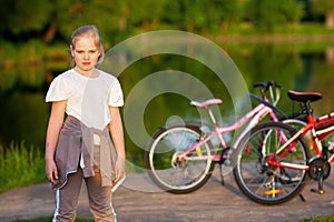 A girl in the park in the evening in the setting sun in stylish sports clothes. Dark green blurred background with