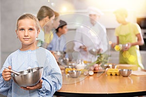 Girl participant in culinary master class is standing with bowl in hands. photo