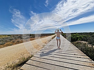 Girl on a path of wooden planks on the sand near Valdelagrana beach, with beautiful clouds in the sky. photo