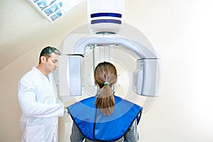 Girl-patient stands in a tomograph, a doctor near the control panel
