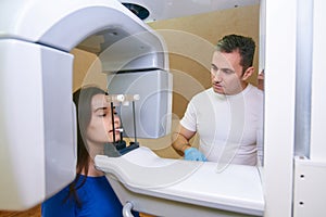 Girl-patient stands in a tomograph, a doctor near the control panel