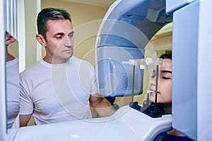 Girl-patient stands in a tomograph, a doctor near the control panel