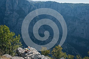 A girl on the peak of mountain opposite the gorge of Vikos in Greece. Vikos gorge in Greece in zagoria. Epirus