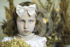 Girl with pearl necklace on her neck and a big bow on her head