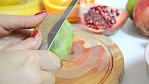 girl peels and cuts kiwi. Sliced orange, kiwi and apples on the table. cuts and peels fresh juicy red orange for a fruit