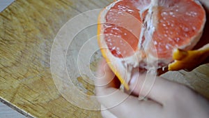 girl peels grapefruit on a cutting board in the kitchen at home. citrus. diet. healthy food. Cutting a grapefruit on two