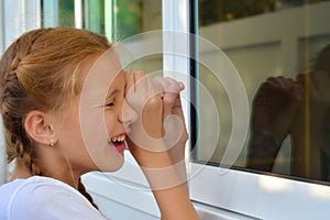 A girl Peeps through the window. Voyeurism. Children`s curiosity.