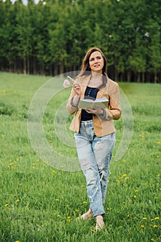 Girl with pen writing on notebook on grass outside