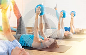Girl performing exercises with pilates ball during group training