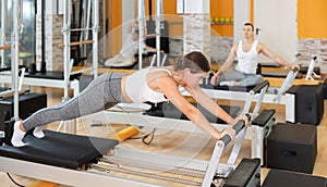 Girl performing exercises on Pilates reformer in fitness studio photo