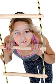 Girl performing gymnastic exercise on rope ladder.