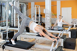 Girl performing pilates exercises on reformer at group workout photo
