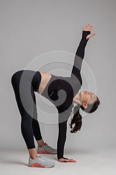 Girl performing stretching workout against grey background