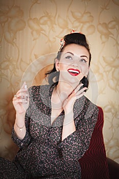 Girl with perfume. Closeup beautiful young woman pretty smiling pinup girl holding bottle of perfume and smelling aroma.